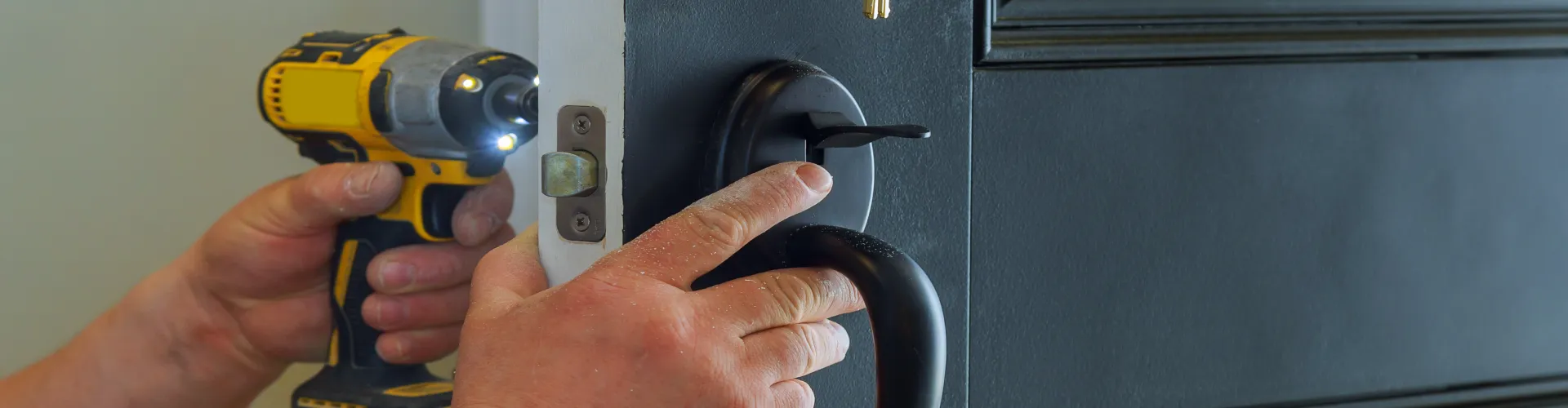 A locksmith from Dr. Locksmith Services is changing a door knob for a residential client.